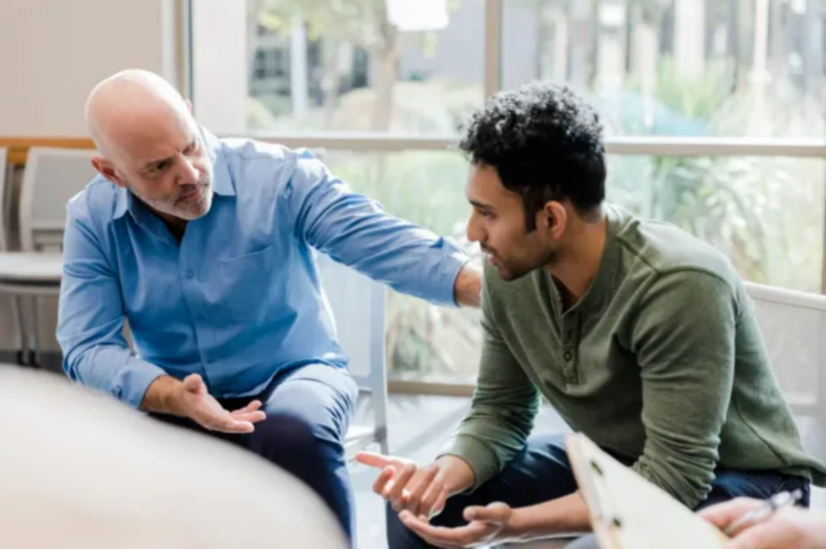 man sitting with an eldery man who is a doctor